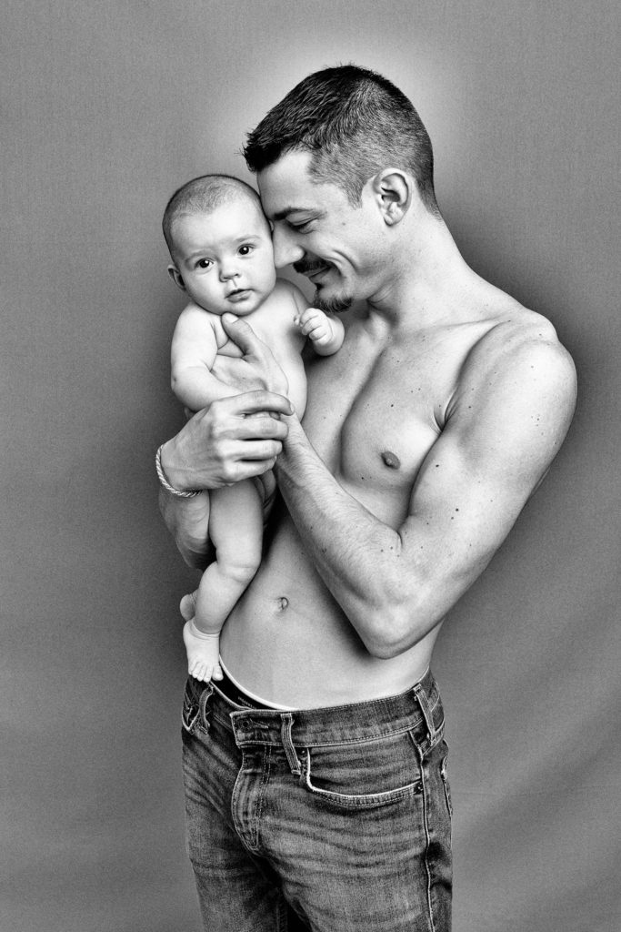 Portrait d'un papa avec son bébé en peau à peau lors d'une séance naissance en studio