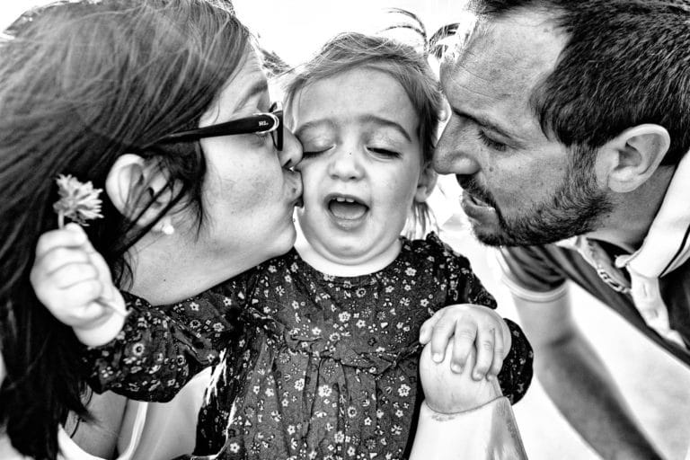 Parents faisant des bisous à leur fille lors d'une séance famille.