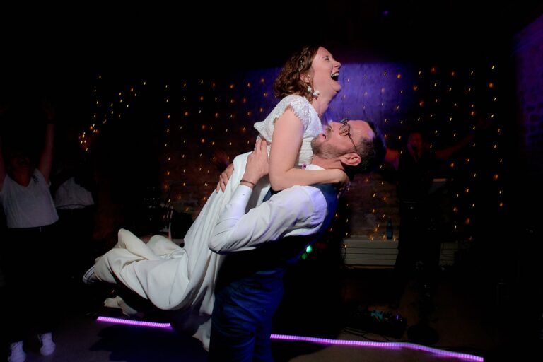 Une mariée en train de rire lors de la première danse. Celle-ci est portée par son mari.
